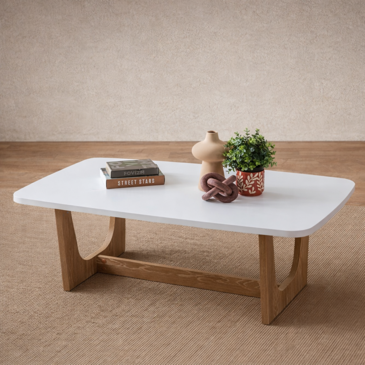 White coffee table with wooden legs on a beige carpet, featuring decorative items.