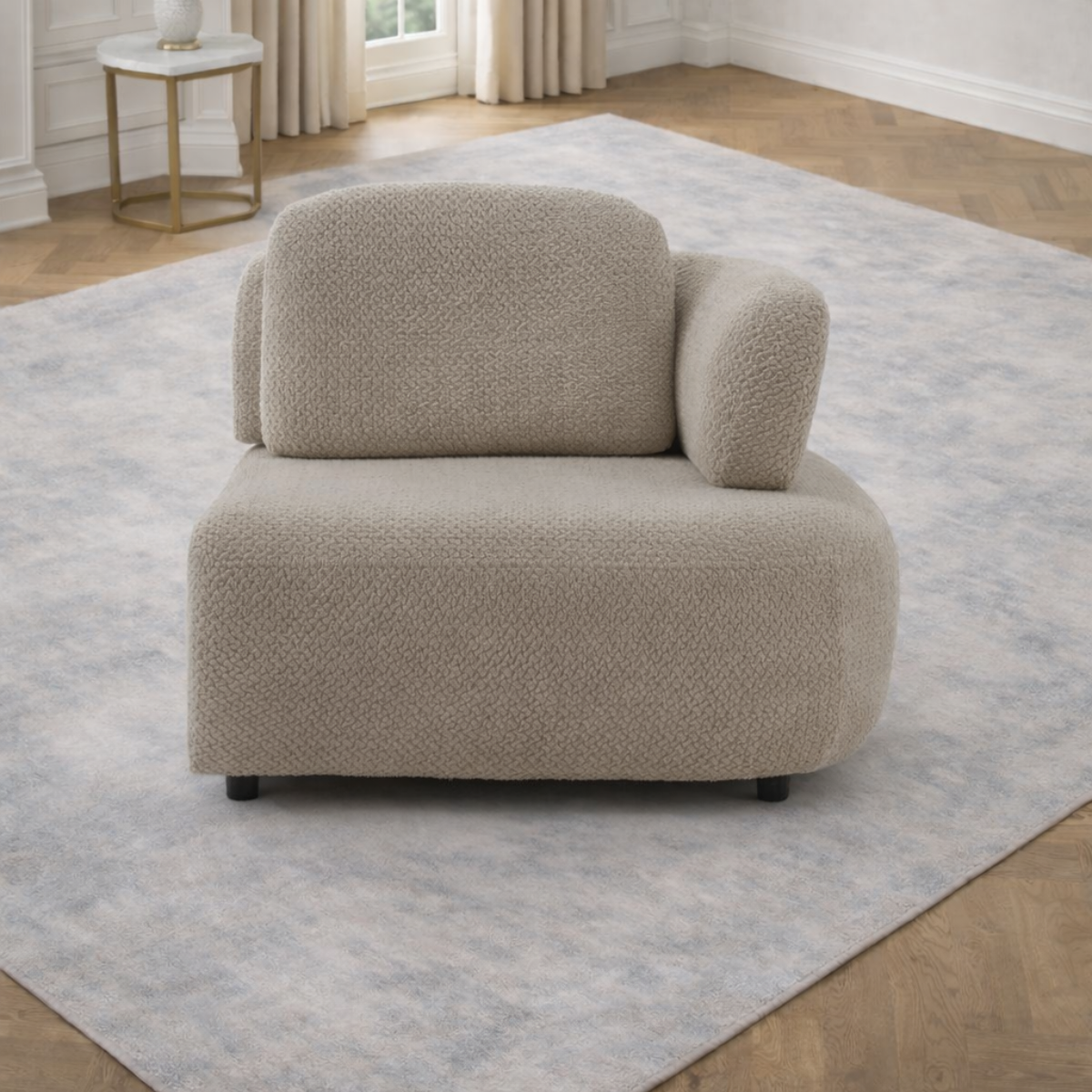 Beige armchair on a light gray rug in a room with a small table and window.