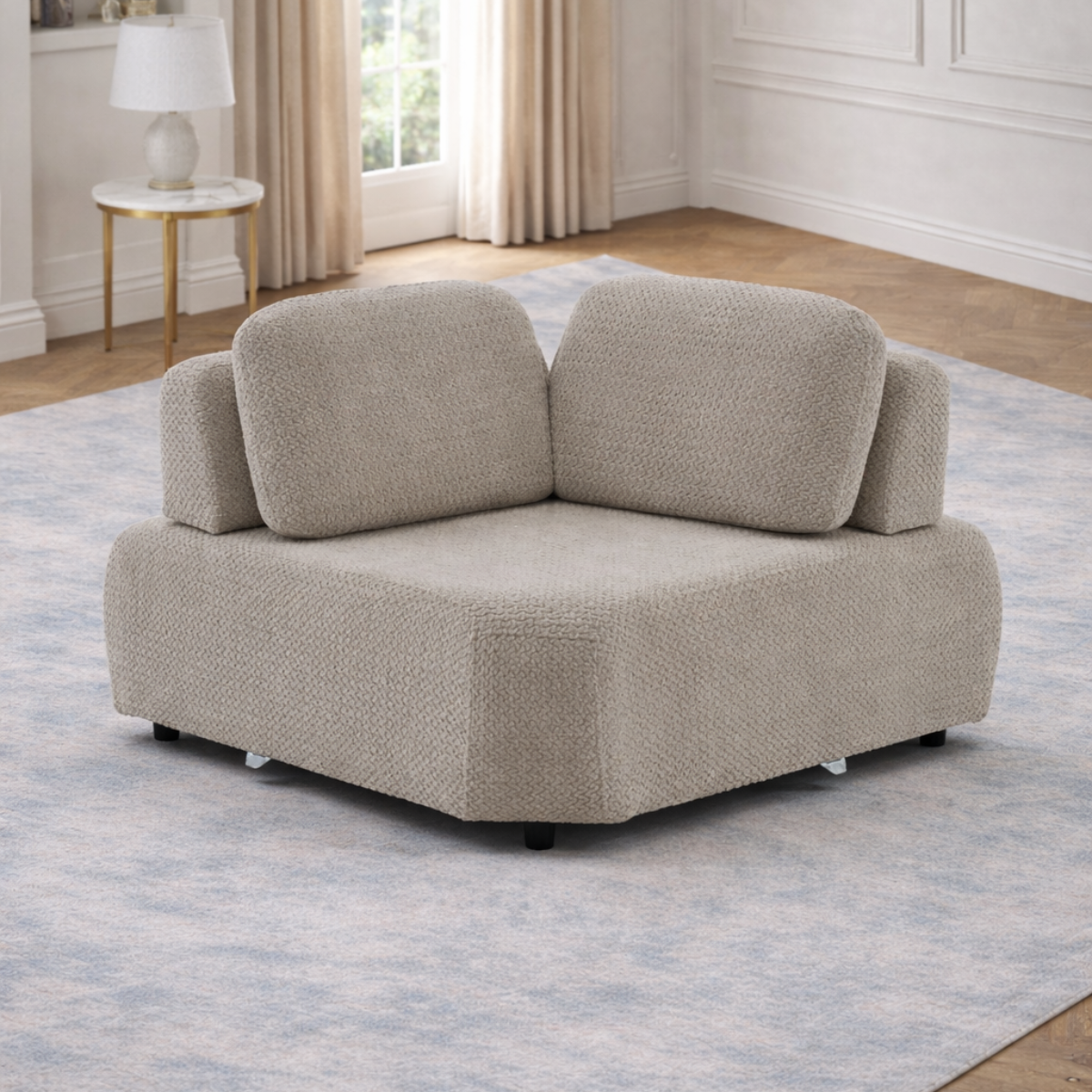 Beige sectional sofa in a living room setting with a rug and side table.