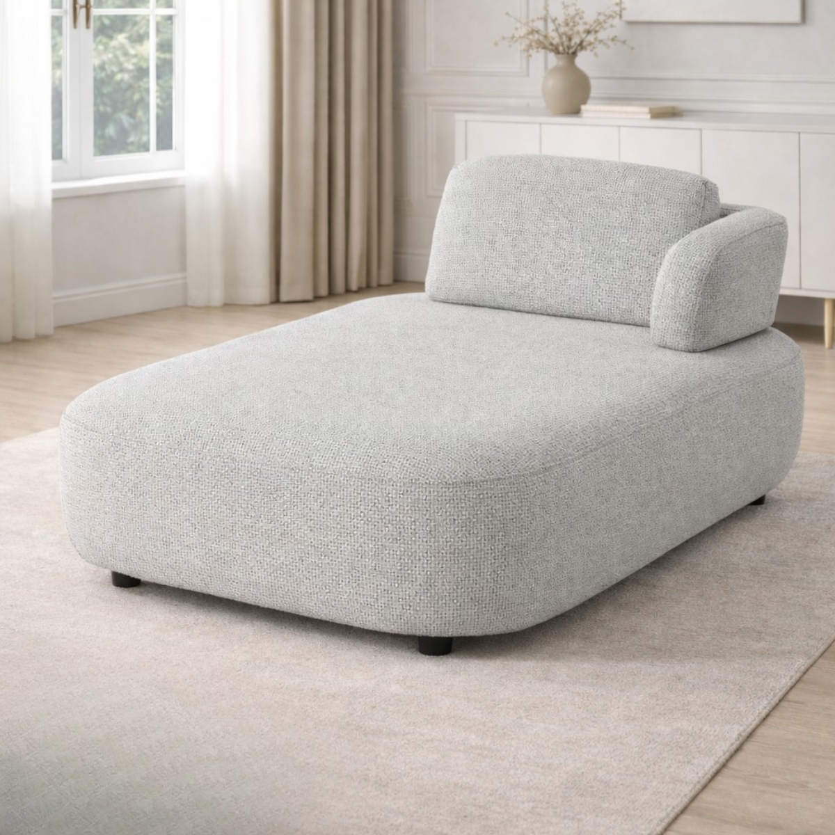 Gray lounge chair in a room with light wood flooring and a window.